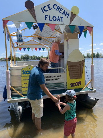 dad giving child an ice cream from a boat on the river